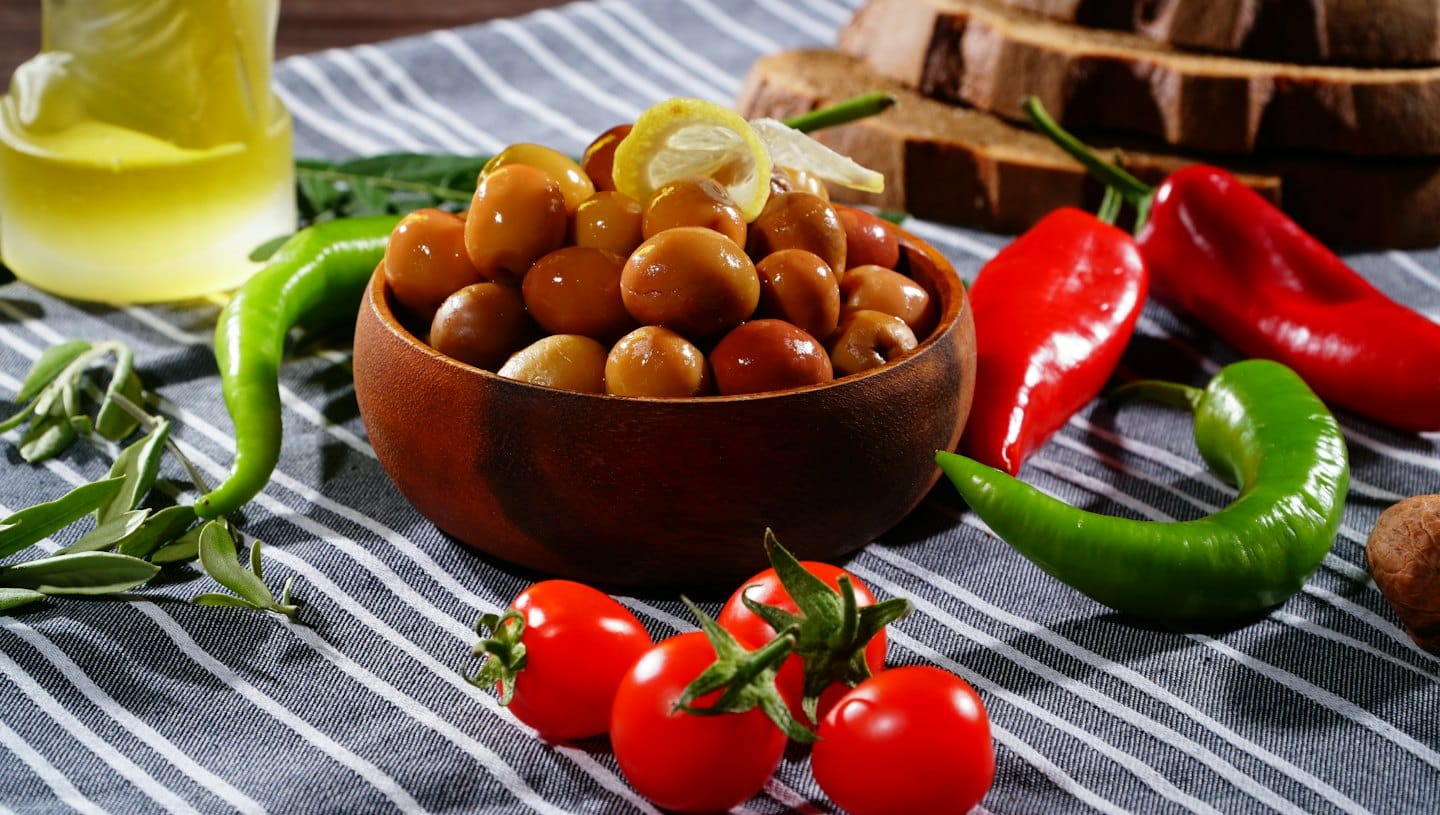 Frische mediterrane Zutaten auf einem gestreiften Tischdecke arrangiert.